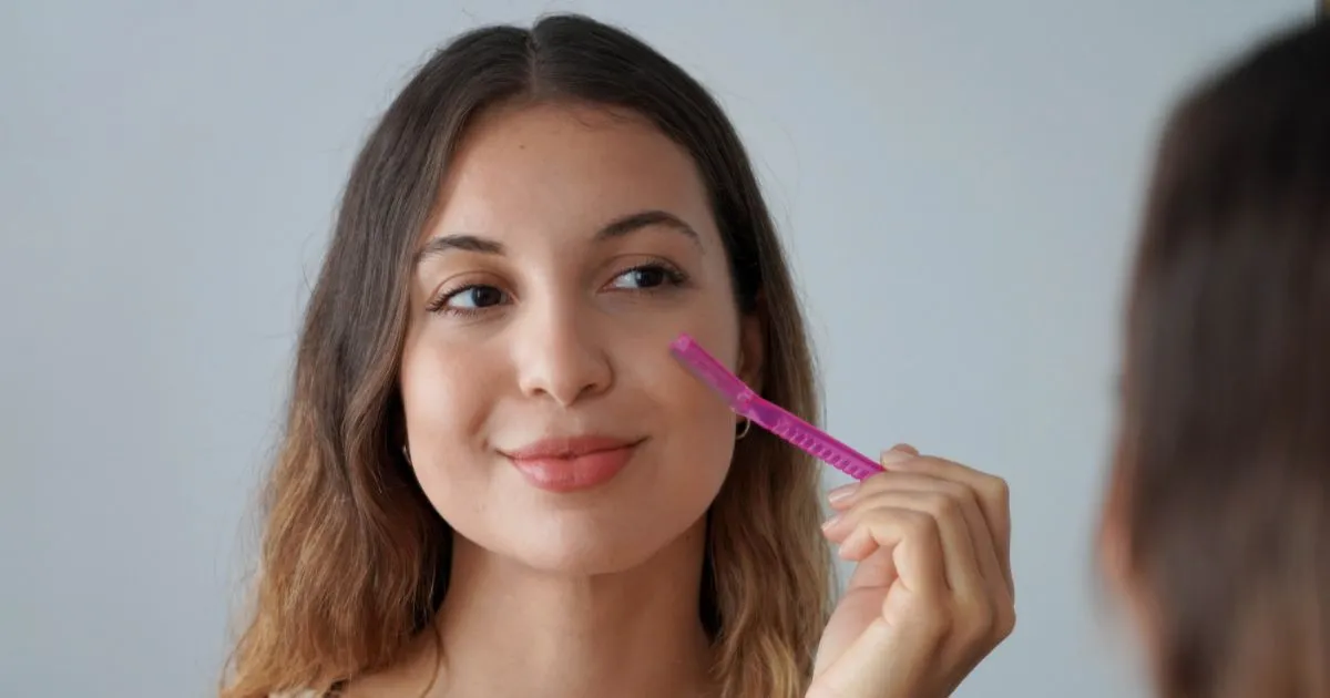Woman performing facial dermaplaning with a pink tool in Florence, KY